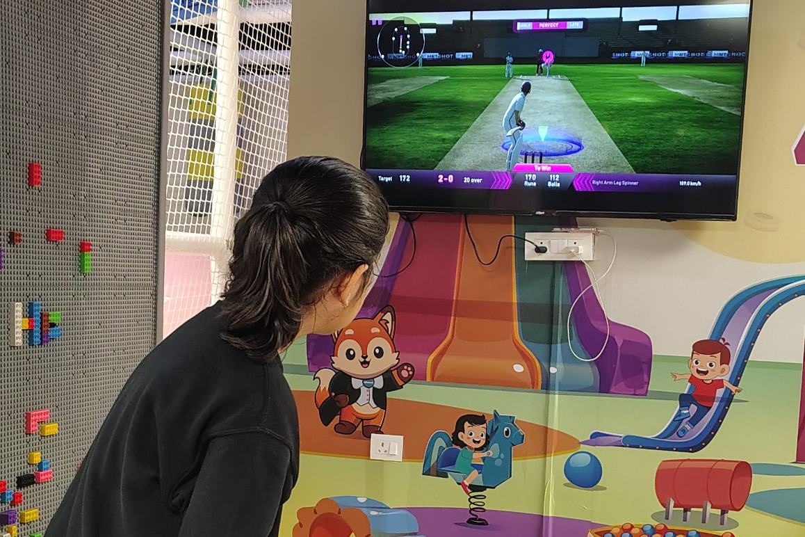 A child batting on the turf strip in front of the interactive cricket screen